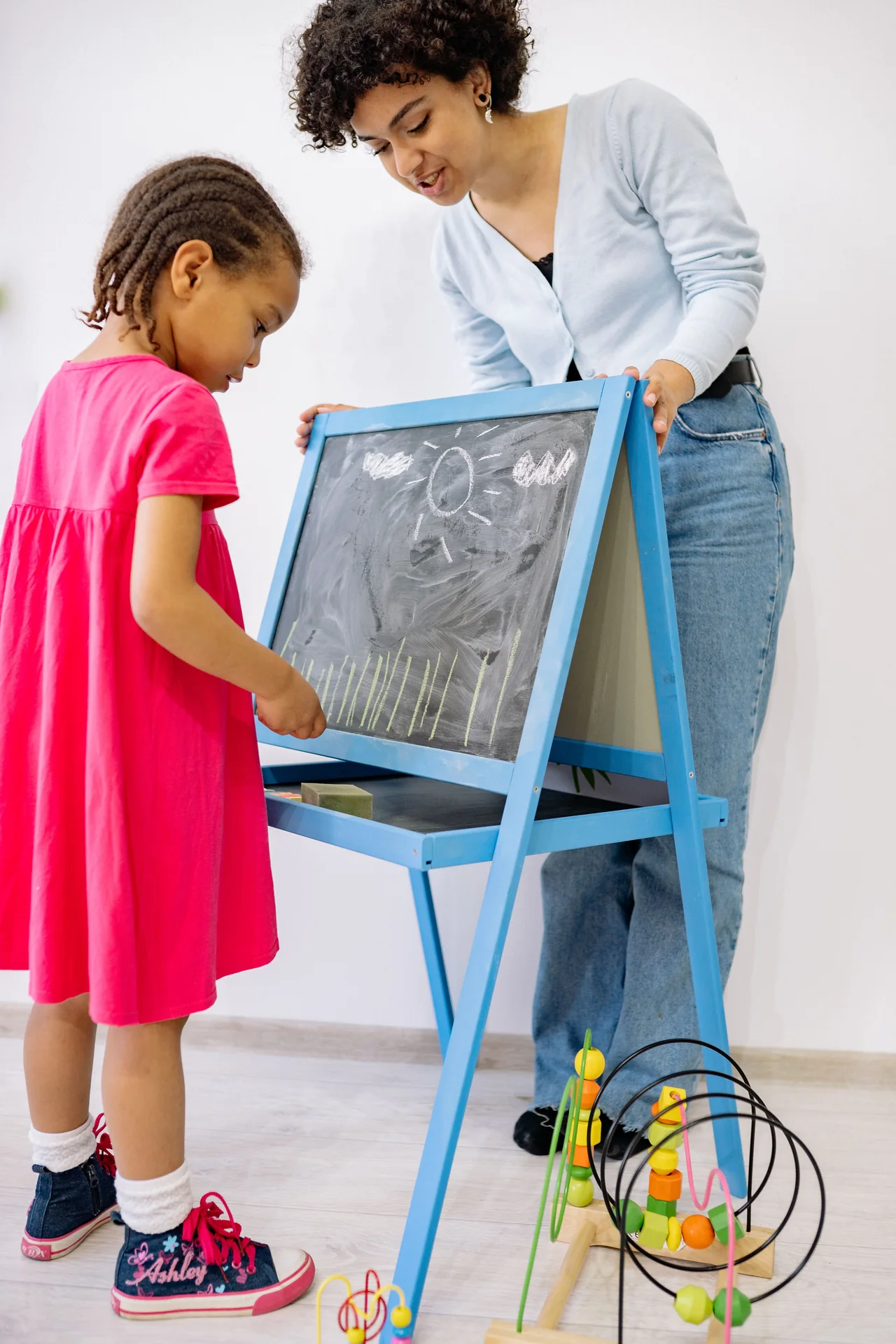 Teacher guiding a young child during a blackboard activity